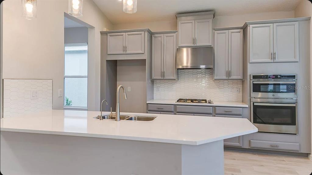 A kitchen with gray cabinets, white countertops, a center island, and stainless steel appliances — 5769 BINNACLE LANE, COCOA, FL