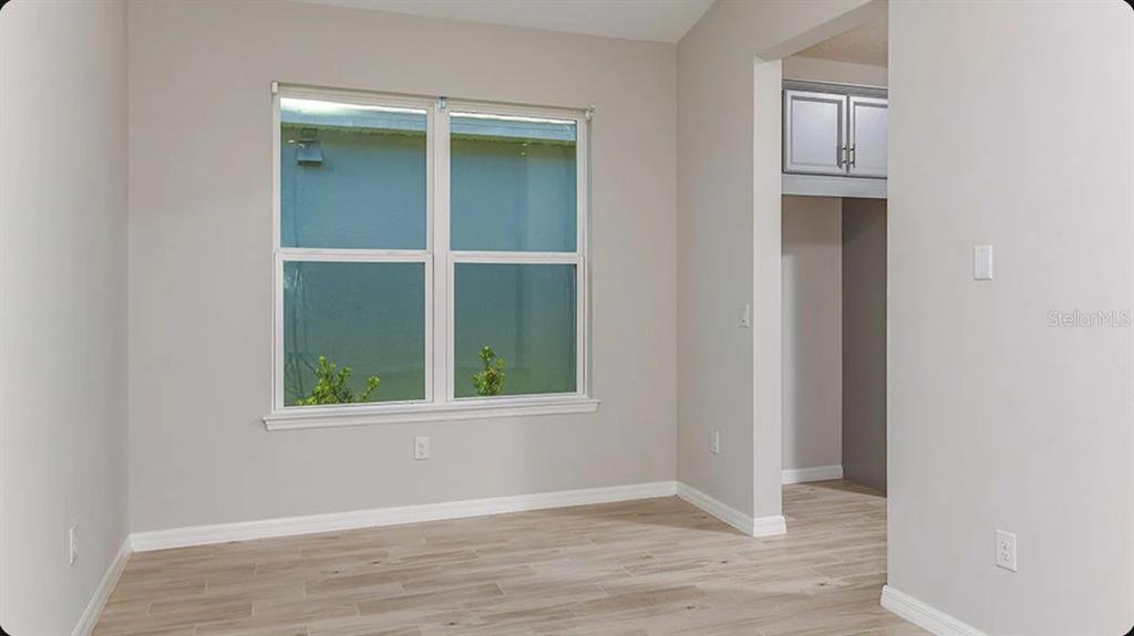 An empty room with light gray walls, wood-look tile flooring, and a large window — 5769 BINNACLE LANE, COCOA, FL