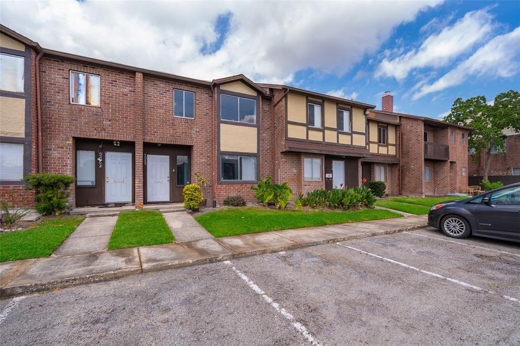 A row of two-story brick and stucco townhomes with a parking lot in the foreground — 5060 DOWNING STREET UNIT 6, ORLANDO, FL