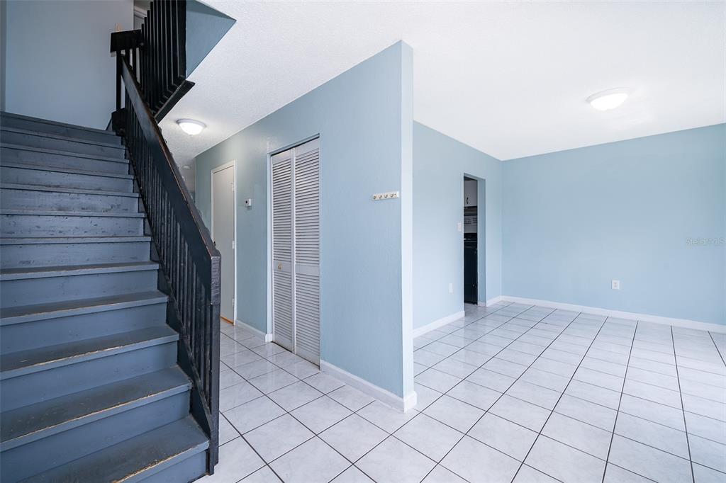 A staircase with a dark railing leads up from a tiled room with blue walls — 5060 DOWNING STREET UNIT 6, ORLANDO, FL