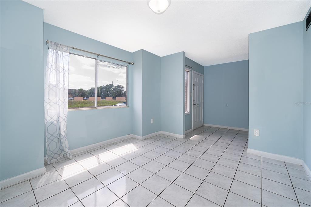 A bright room with light blue walls, white tile flooring, and a large window — 5060 DOWNING STREET UNIT 6, ORLANDO, FL