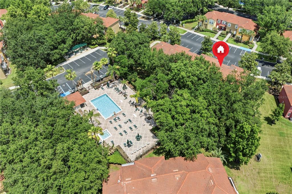 An aerial view shows a community swimming pool surrounded by trees and residential buildings — 8564 CRYSTAL COVE LOOP, KISSIMMEE, FL