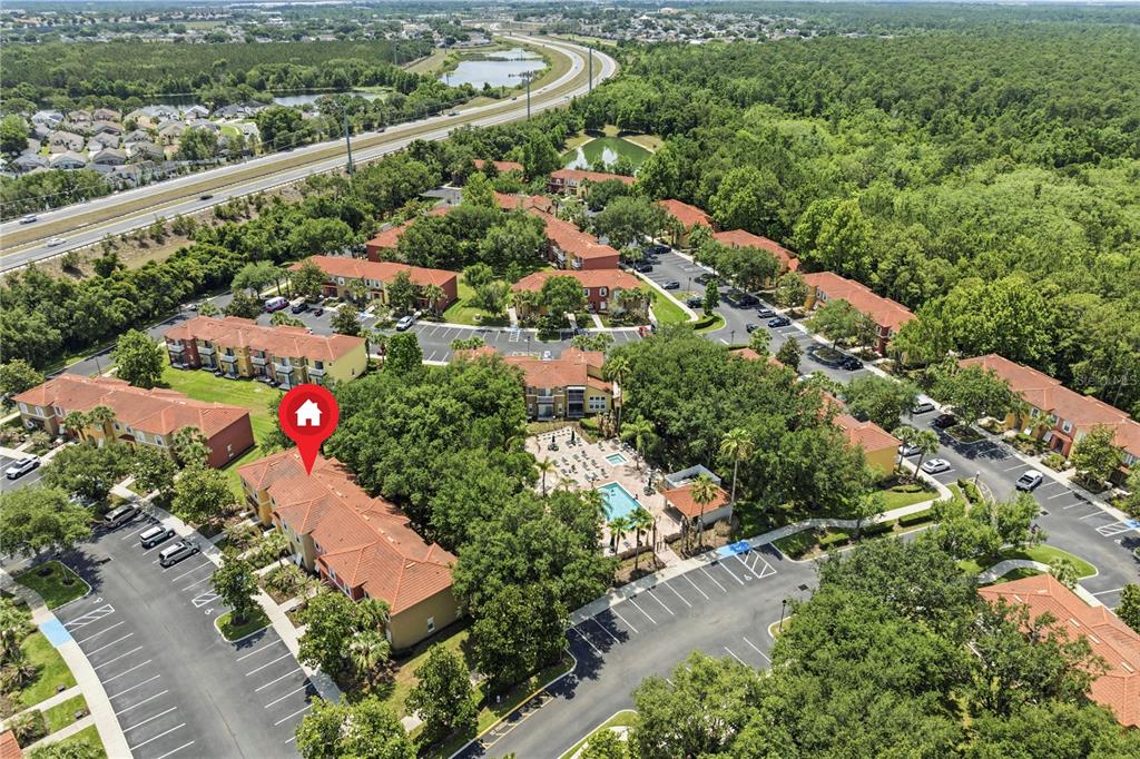 An aerial view shows a multi-building apartment complex with a central pool and parking lots — 8564 CRYSTAL COVE LOOP, KISSIMMEE, FL