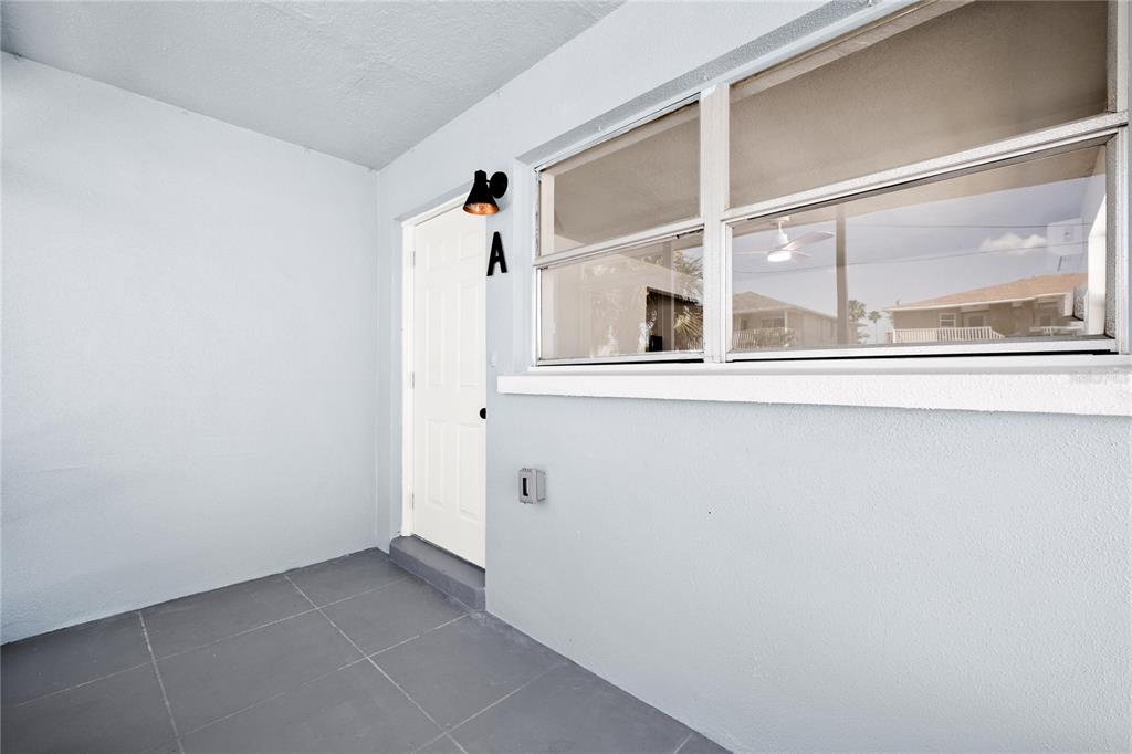 A covered entryway features a white door labeled A, a wall-mounted light, and tiled flooring — 13388 1ST STREET E, MADEIRA BEACH, FL