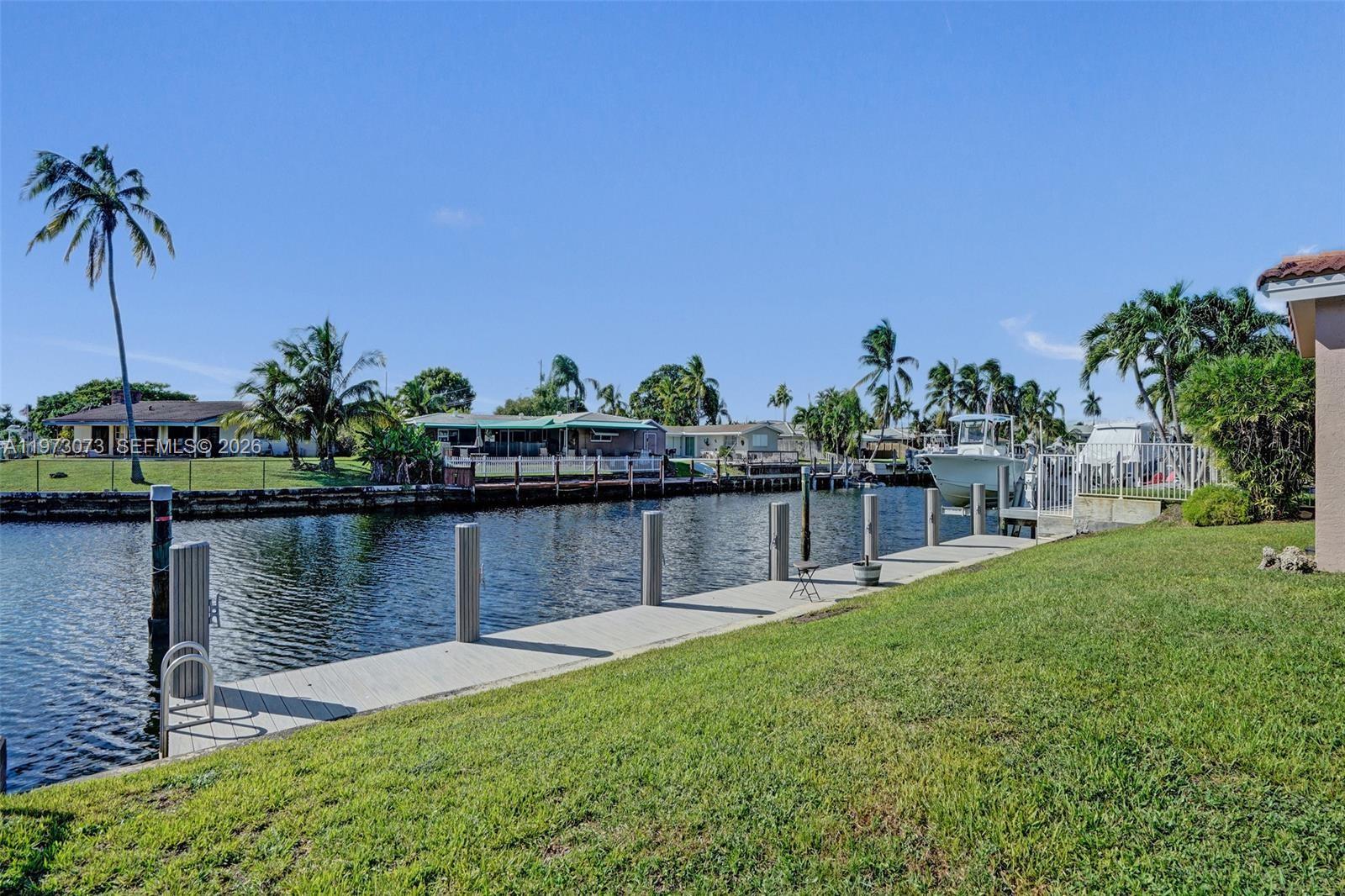 A concrete dock extends along a canal lined with houses and palm trees — 949 SE 10th Ct, Pompano Beach FL 33060, POMPANO BEACH, FL
