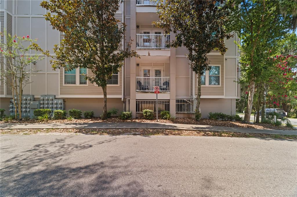 A multi-story apartment building exterior features balconies, tan siding, and a paved parking area — 835 SW 9TH STREET UNIT 101, GAINESVILLE, FL