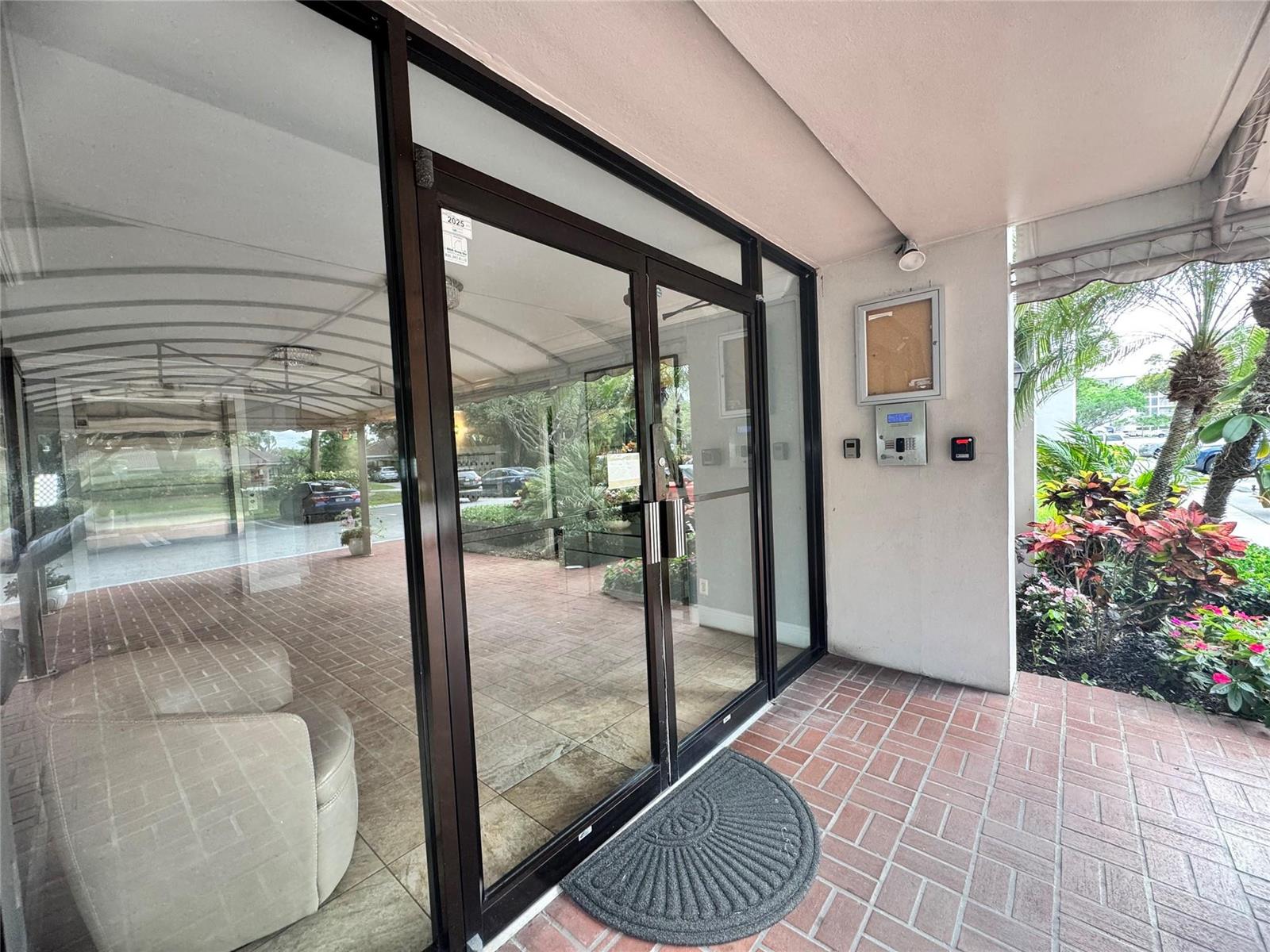 A glass double door entrance leads into a building with a brick-paved covered walkway — 2850 N Palm Aire Drive # 207, Pompano Beach FL 33069, POMPANO BEACH, FL