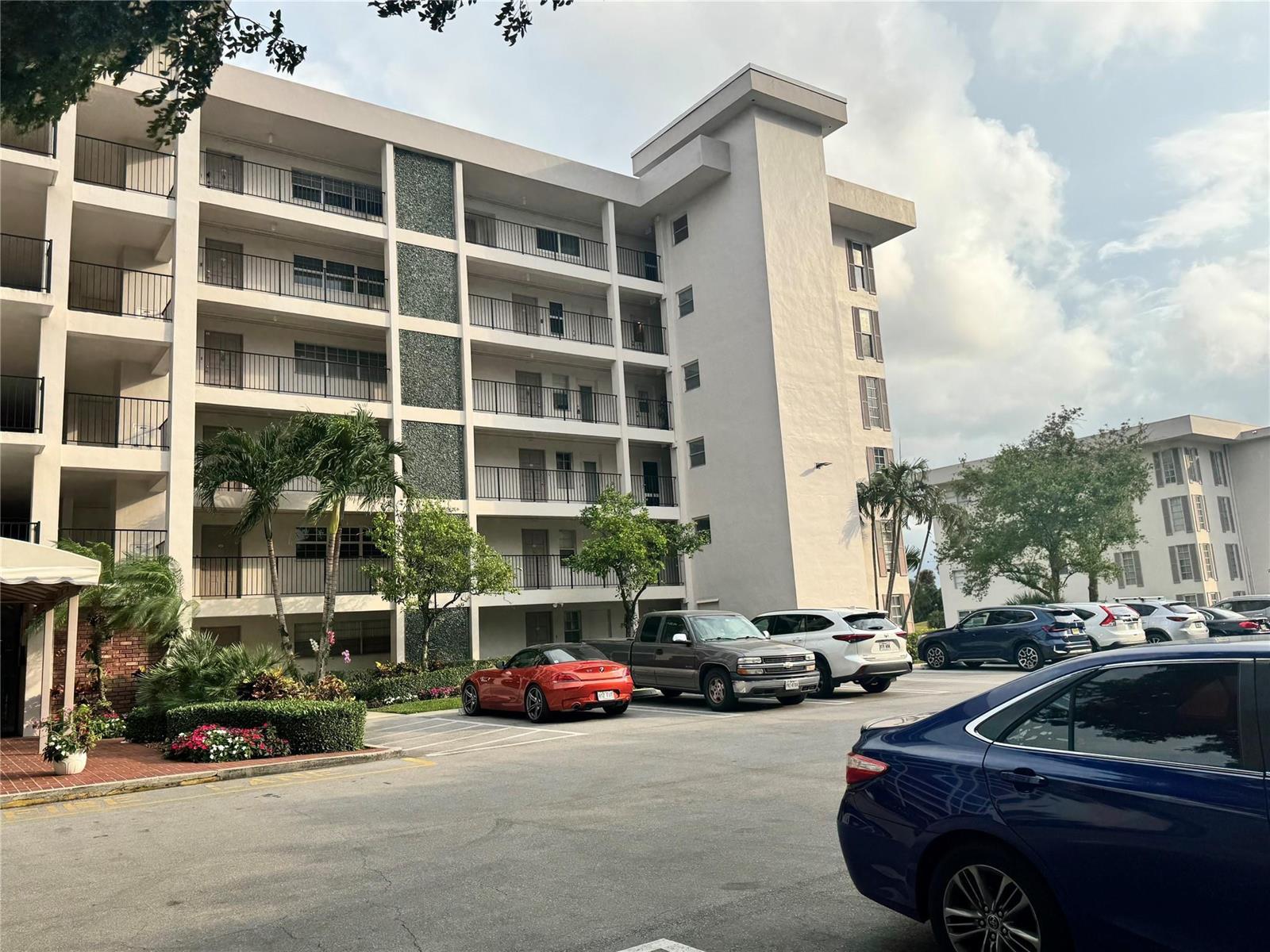 A multi-story apartment building with balconies and a parking lot in the foreground — 2850 N Palm Aire Drive # 207, Pompano Beach FL 33069, POMPANO BEACH, FL