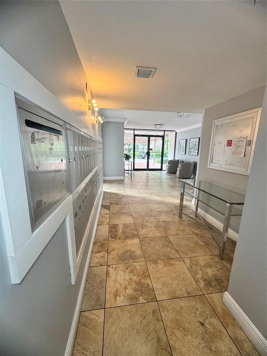 An apartment building lobby features a wall of metal mailboxes, tile flooring, and glass doors — 2850 N Palm Aire Drive # 207, Pompano Beach FL 33069, POMPANO BEACH, FL