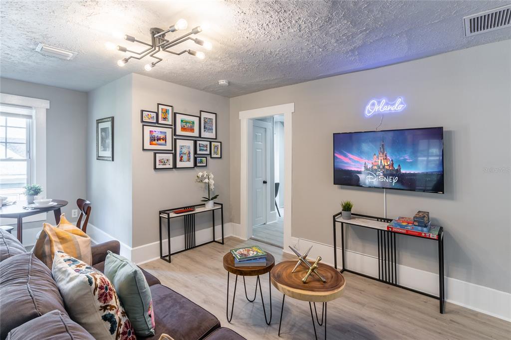 A living room features a grey sofa, two wood-topped coffee tables, and a wall-mounted television — 515.5 DANIELS AVENUE, ORLANDO, FL