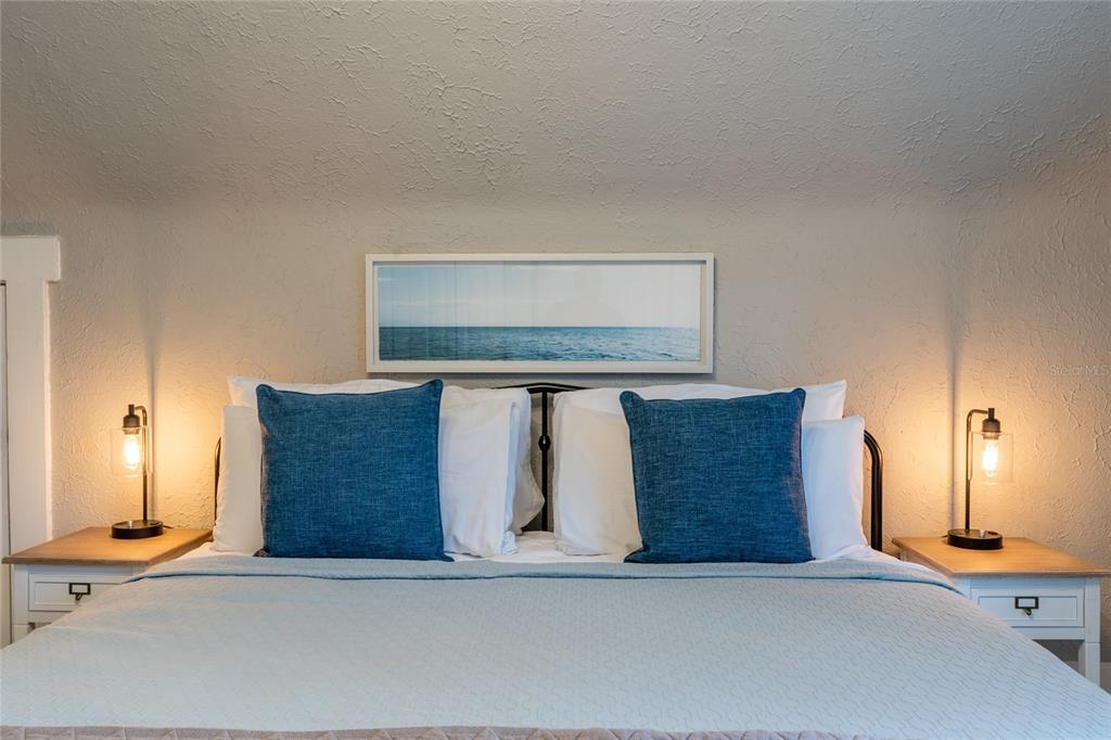 A bedroom features a bed with blue pillows, two bedside lamps, and a framed ocean print — 515.5 DANIELS AVENUE, ORLANDO, FL