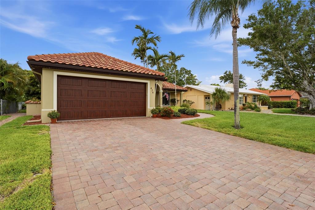 A paved driveway leads to a house with a brown garage door and tile roof — 424 PENSACOLA ROAD, VENICE, FL