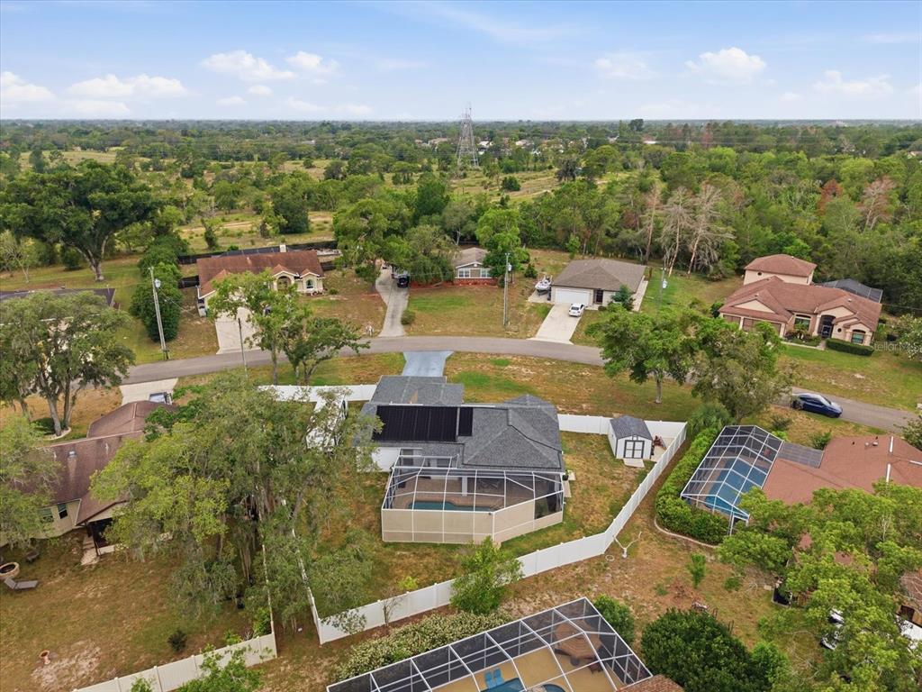 An aerial view shows several suburban houses with swimming pools and fenced backyards — 2478 GLENRIDGE DR, SPRING HILL, FL