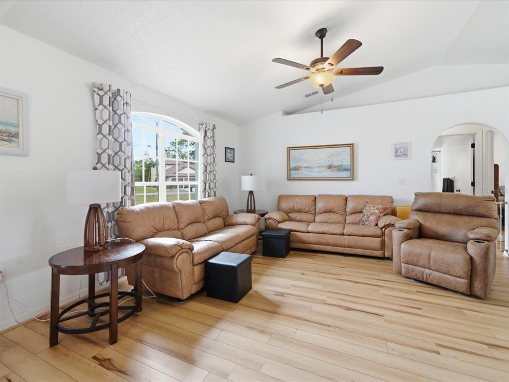 A living room features light wood flooring, tan leather furniture, and a ceiling fan — 2478 GLENRIDGE DR, SPRING HILL, FL