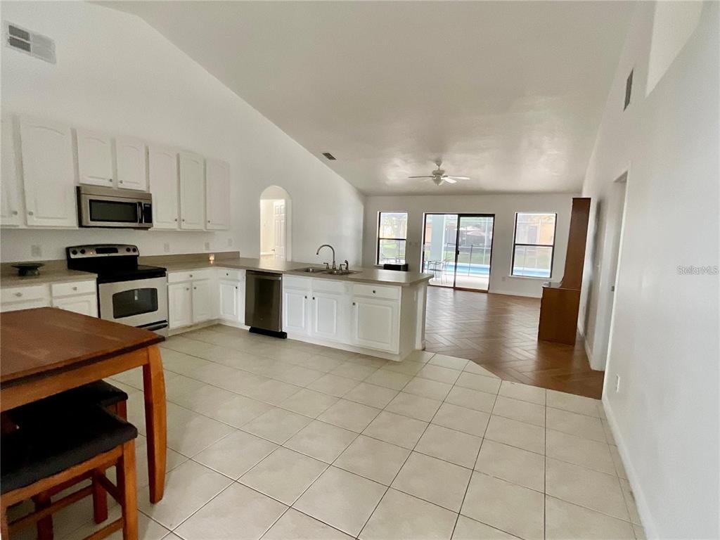 A kitchen with white cabinets and a breakfast bar opens into a living area — 511 COVENTRY ROAD, DAVENPORT, FL