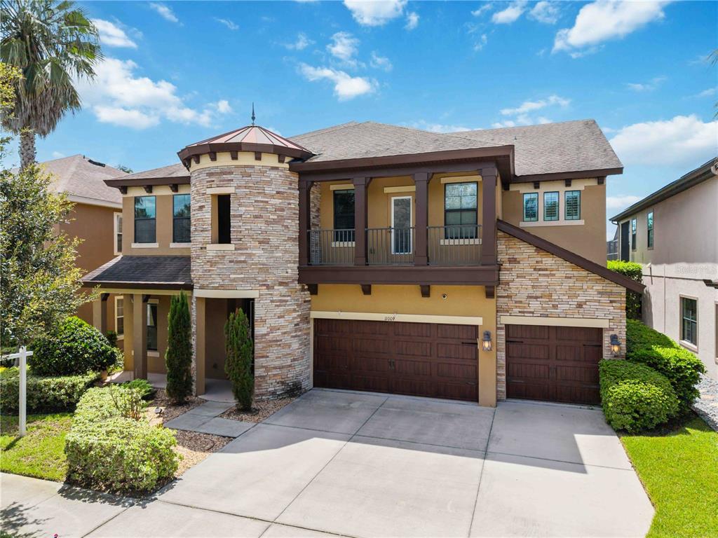 A two-story suburban house with a stone turret, a balcony, and a three-car garage — 11009 CHARMWOOD DRIVE, RIVERVIEW, FL