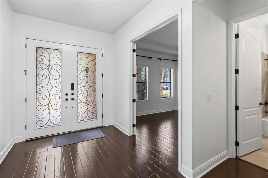 An entryway with dark wood floors, a double front door with decorative glass, and white walls — 11009 CHARMWOOD DRIVE, RIVERVIEW, FL