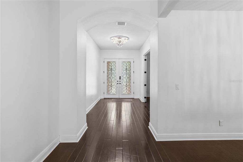 A bright entryway features dark hardwood floors, white walls, and a decorative double front door — 11009 CHARMWOOD DRIVE, RIVERVIEW, FL