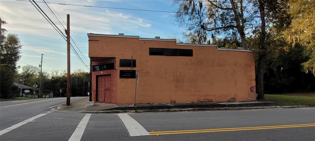 A single-story, orange-painted commercial building sits on a corner lot next to a road — 24422 W US 27 HIGHWAY, HIGH SPRINGS, FL