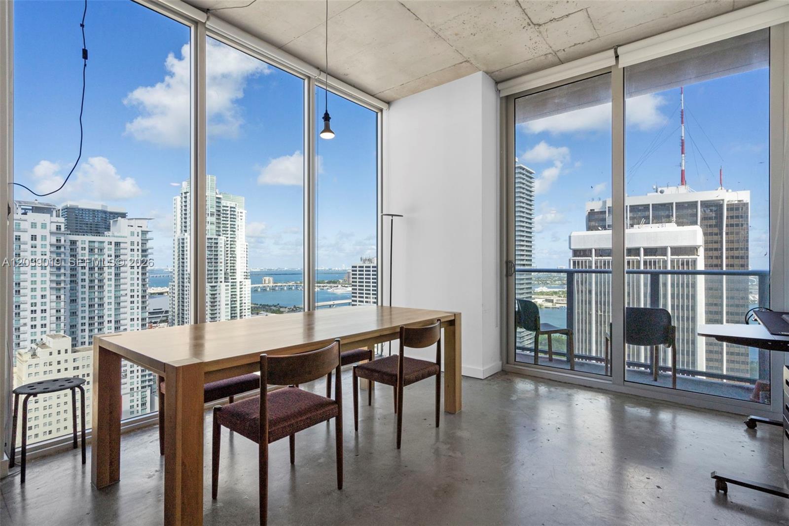 A dining area with floor-to-ceiling windows, concrete ceilings, and a view of the city skyline — 151 SE 1st St # 3102, Miami FL 33131, MIAMI, FL