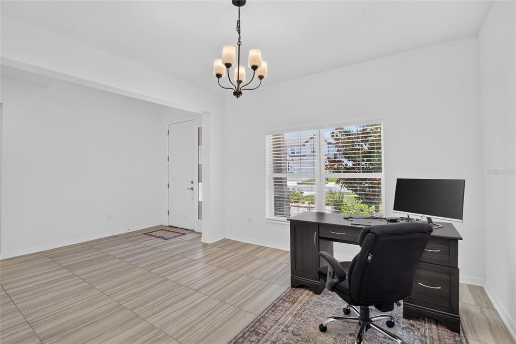 A home office with tile flooring, a desk, a rolling chair, and a chandelier — 7321 GULF CYPRESS AVENUE, LAND O LAKES, FL