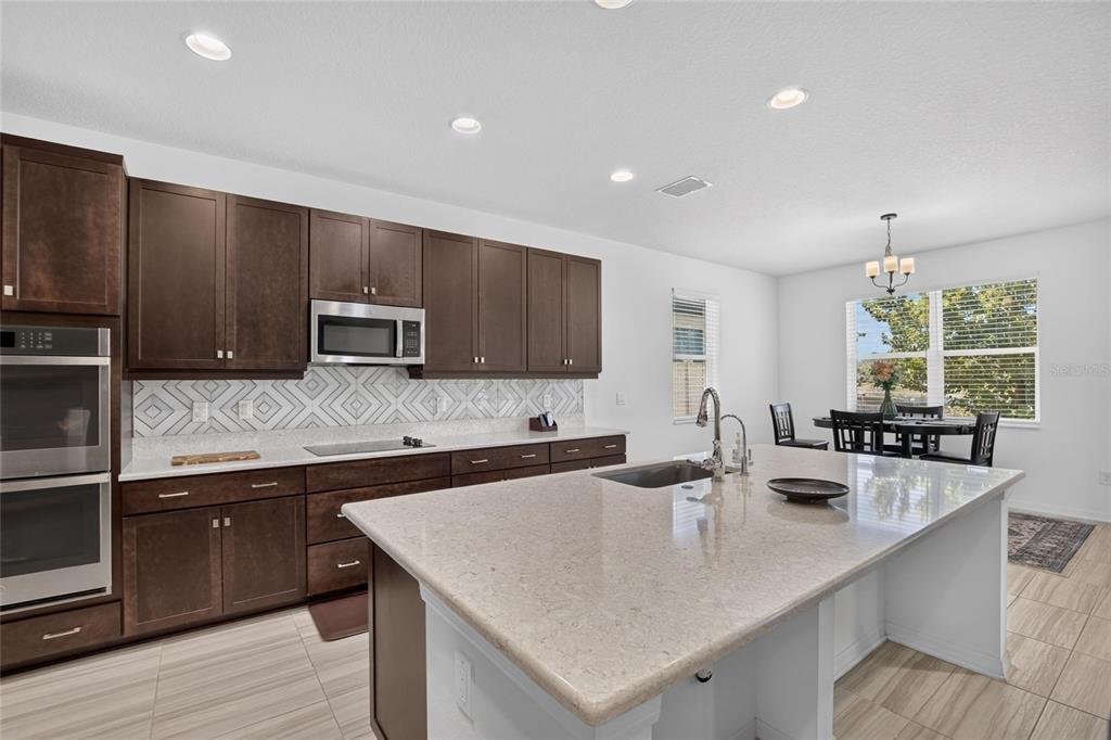 A kitchen with dark wood cabinets, a large island, and a dining area with windows — 7321 GULF CYPRESS AVENUE, LAND O LAKES, FL