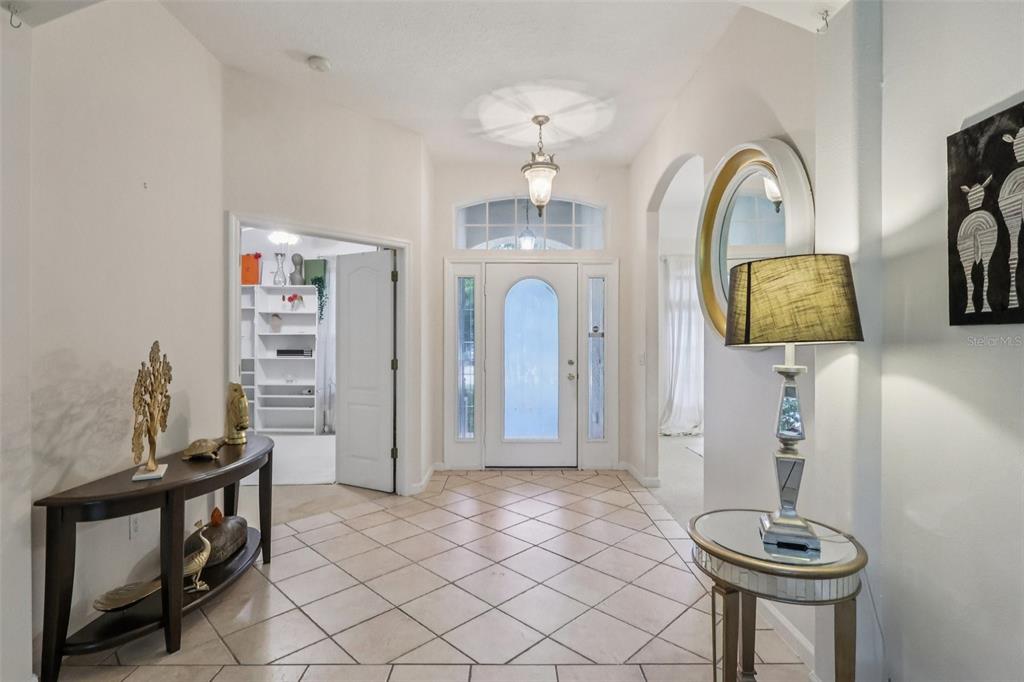 A tiled entryway features a front door with sidelights, a console table, and a lamp — 3848 LONG BRANCH LANE, APOPKA, FL