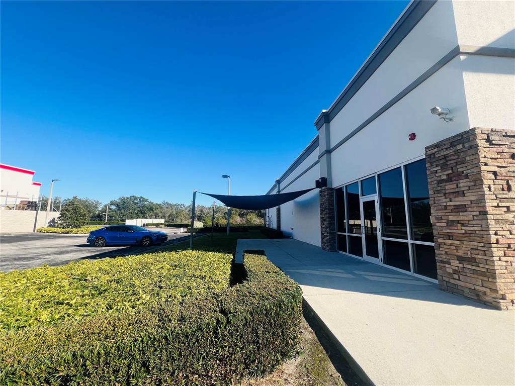 A blue car is parked near a modern commercial building with a stone facade — 2507 LAKEWOOD RANCH BOULEVARD, BRADENTON, FL