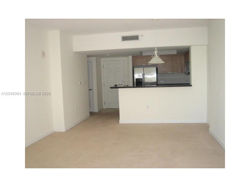 This interior view shows a carpeted living area adjacent to an open kitchen with cabinets — 140 S DIXIE HY # 502, Hollywood FL 33020, HOLLYWOOD, FL