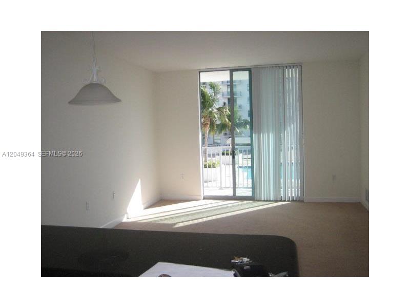 This living room features beige carpeting, a pendant light, and a sliding glass door — 140 S DIXIE HY # 502, Hollywood FL 33020, HOLLYWOOD, FL