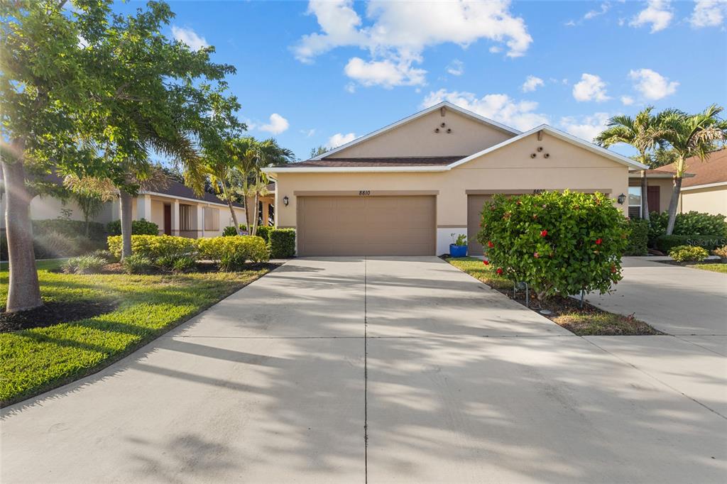A tan single-story house with a two-car garage and a concrete driveway — 8810 TUSCANY ISLES DRIVE, PUNTA GORDA, FL