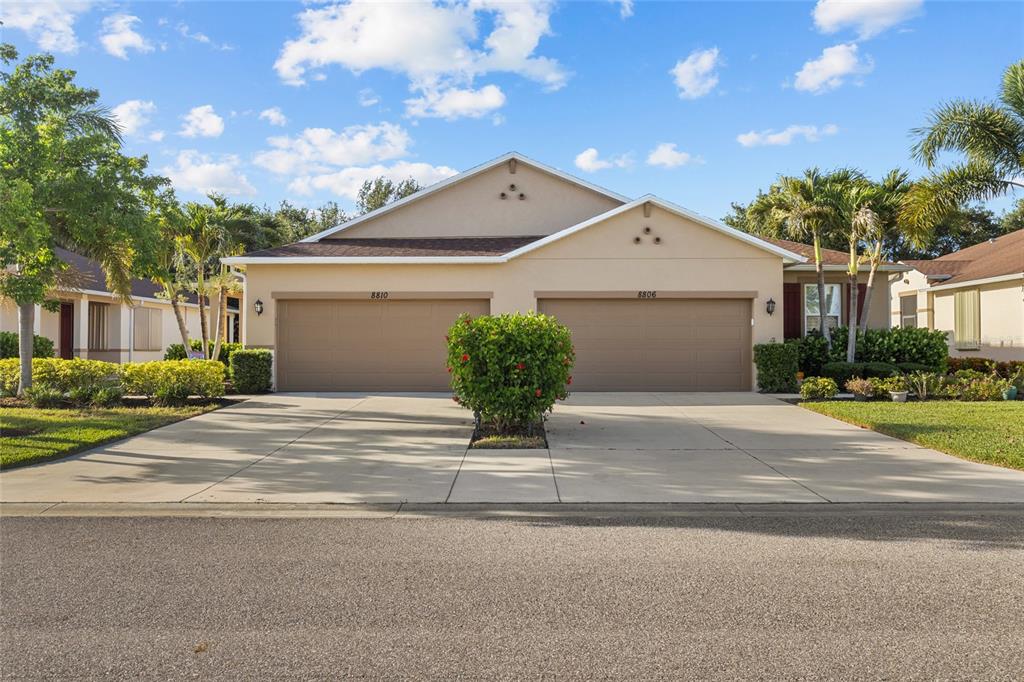 A duplex house with two garage doors and a central bush in the driveway — 8810 TUSCANY ISLES DRIVE, PUNTA GORDA, FL