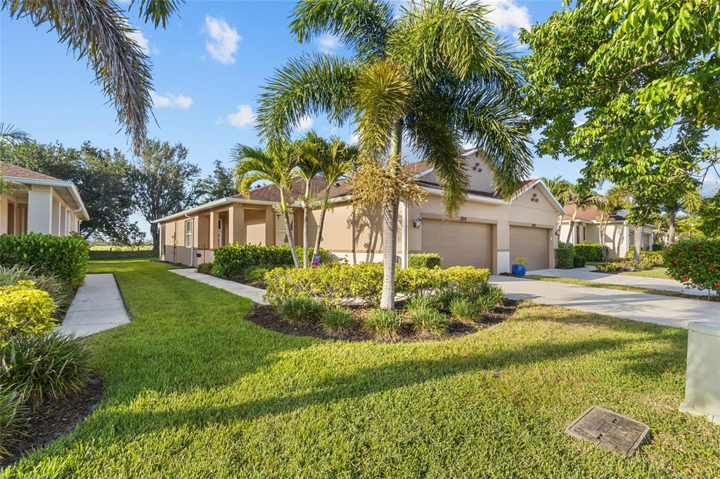 A tan one-story house with a two-car garage and palm trees in the front yard — 8810 TUSCANY ISLES DRIVE, PUNTA GORDA, FL
