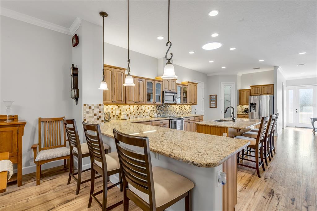 A living room with a fireplace, wood-look flooring, and an open view into the kitchen — 3367 TORRE BOULEVARD, NEW SMYRNA BEACH, FL