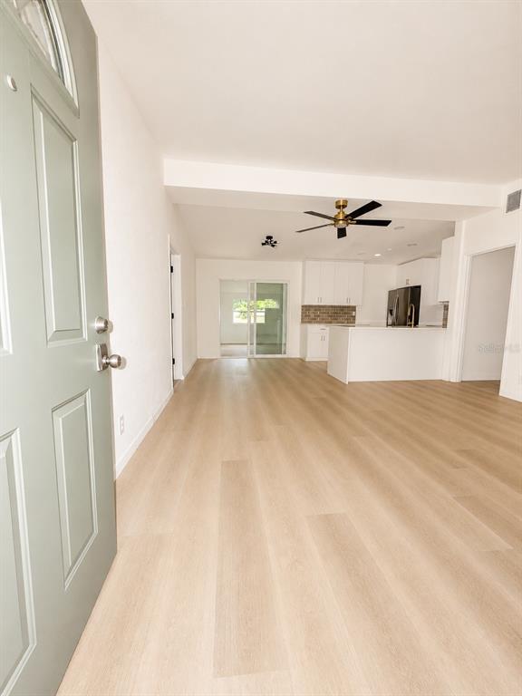 An open-concept living area features light wood-look flooring, white walls, and a modern kitchen — 2827 S PARK AVENUE, SANFORD, FL