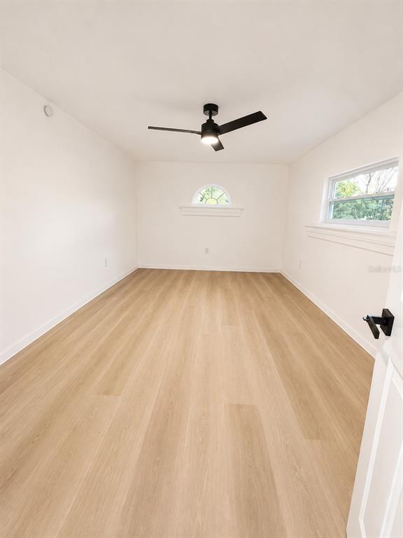 An empty room features light wood-look flooring, white walls, a ceiling fan, and two windows — 2827 S PARK AVENUE, SANFORD, FL