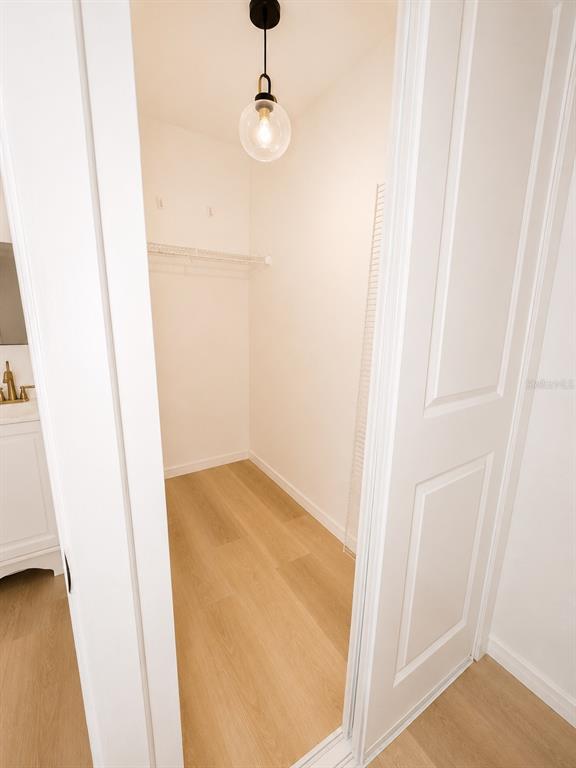 A small walk-in closet features light wood flooring, white walls, and a single pendant light — 2827 S PARK AVENUE, SANFORD, FL