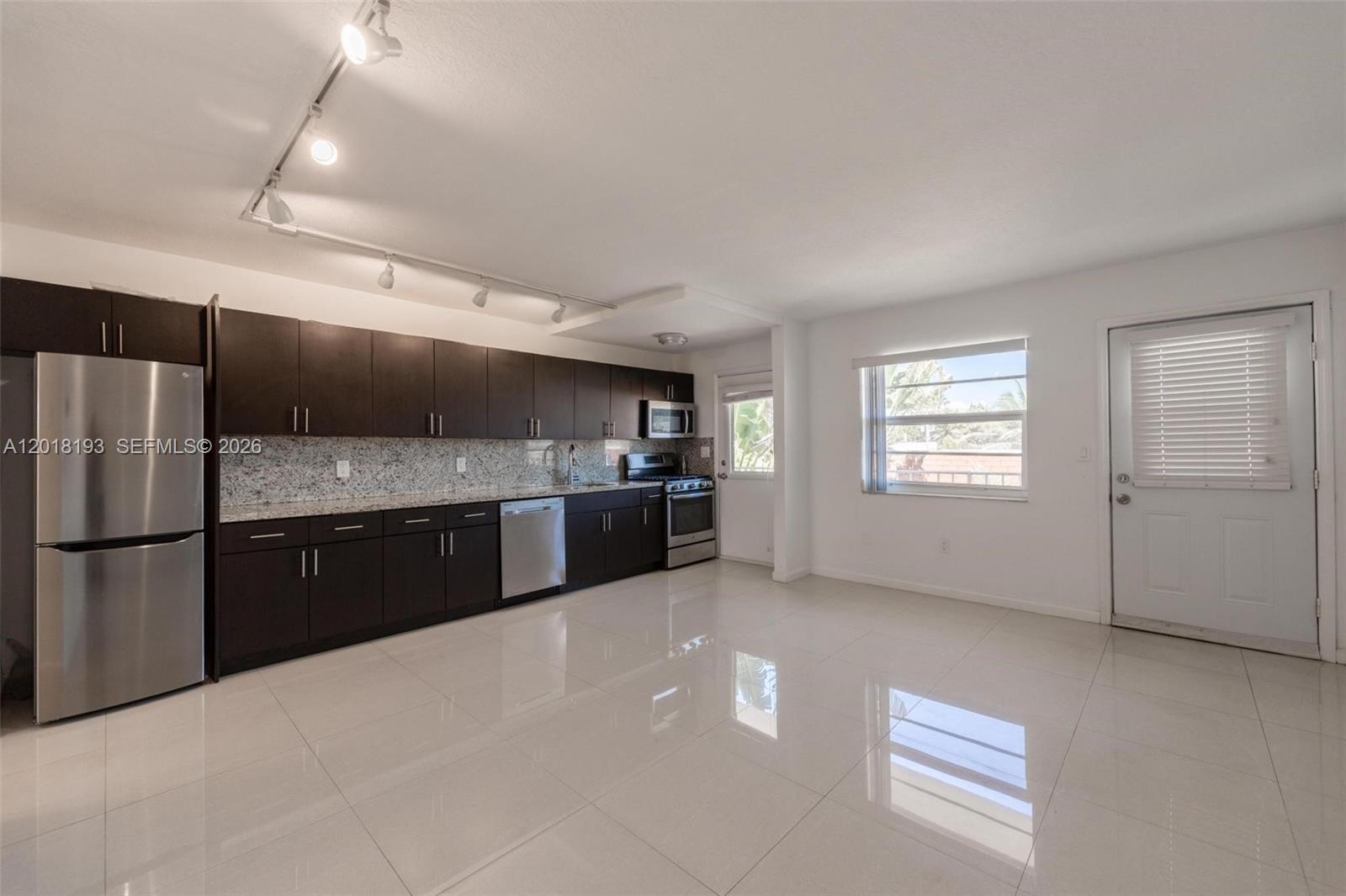 A kitchen with dark cabinets, stainless steel appliances, and light tile flooring — 525 Meridian Ave # 305, Miami Beach FL 33139, MIAMI BEACH, FL