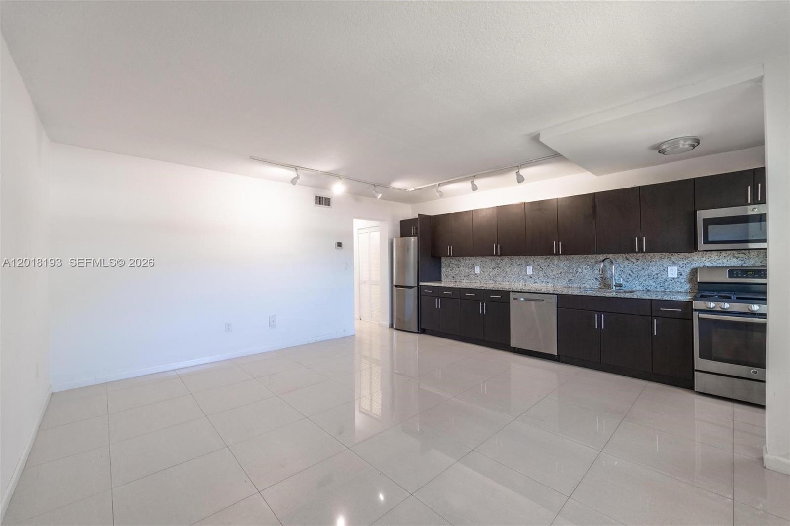 A kitchen with dark cabinets, stainless steel appliances, and light tile flooring — 525 Meridian Ave # 305, Miami Beach FL 33139, MIAMI BEACH, FL