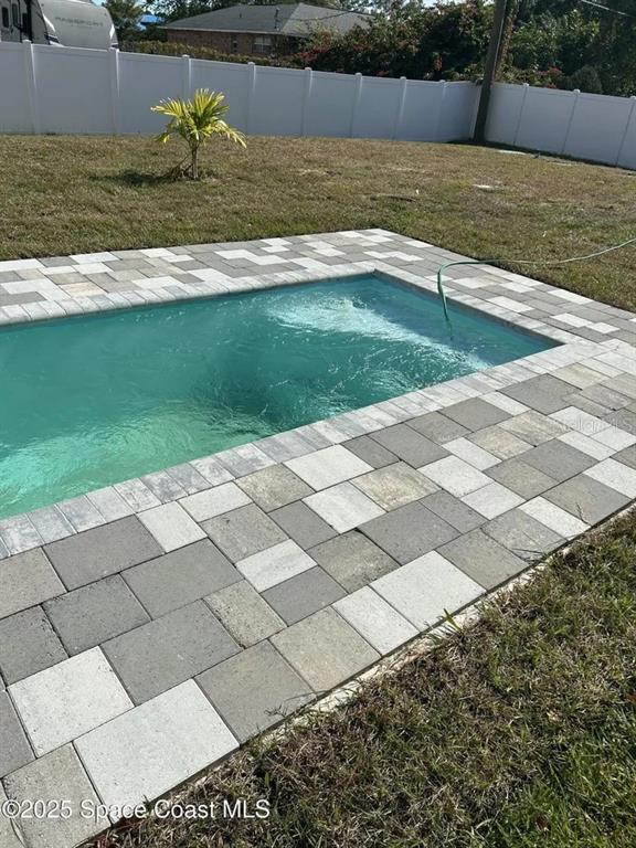 A rectangular swimming pool is surrounded by a multi-toned paver patio in a backyard — 435 GOLDSMITH AVENUE NW, PALM BAY, FL