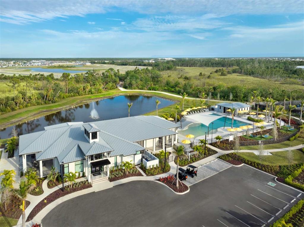An aerial view of a community clubhouse with a pool, parking lot, and pond — 12024 ETHOS COURT, VENICE, FL