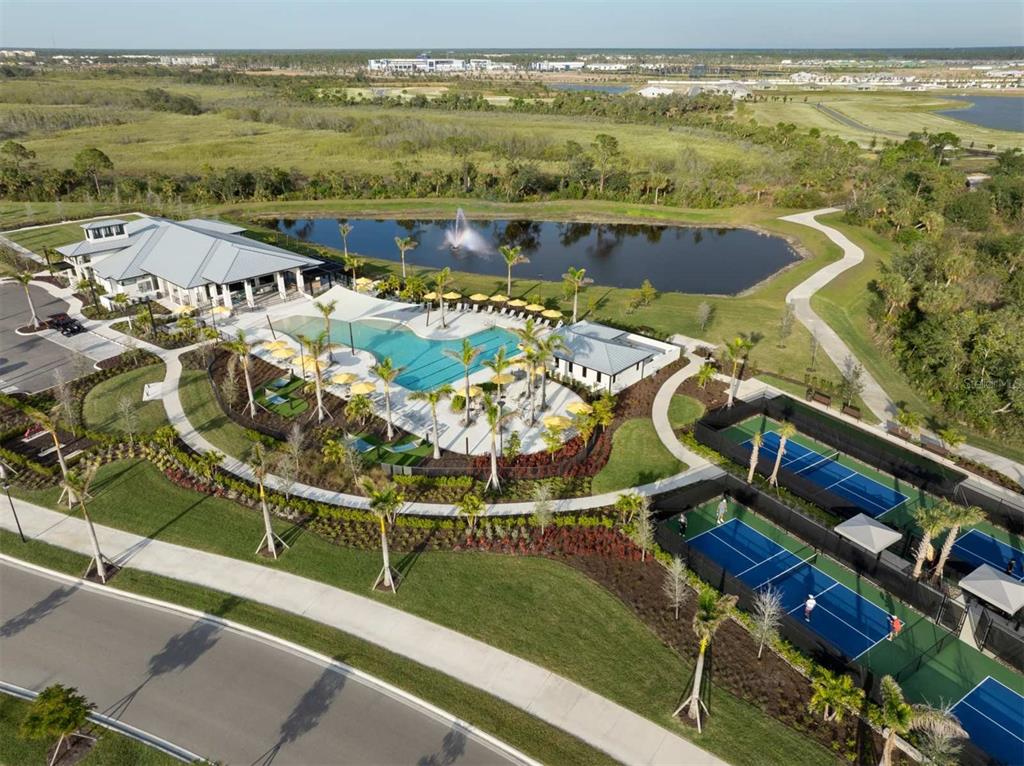 An aerial view of a community amenity center featuring a swimming pool and tennis courts — 12024 ETHOS COURT, VENICE, FL