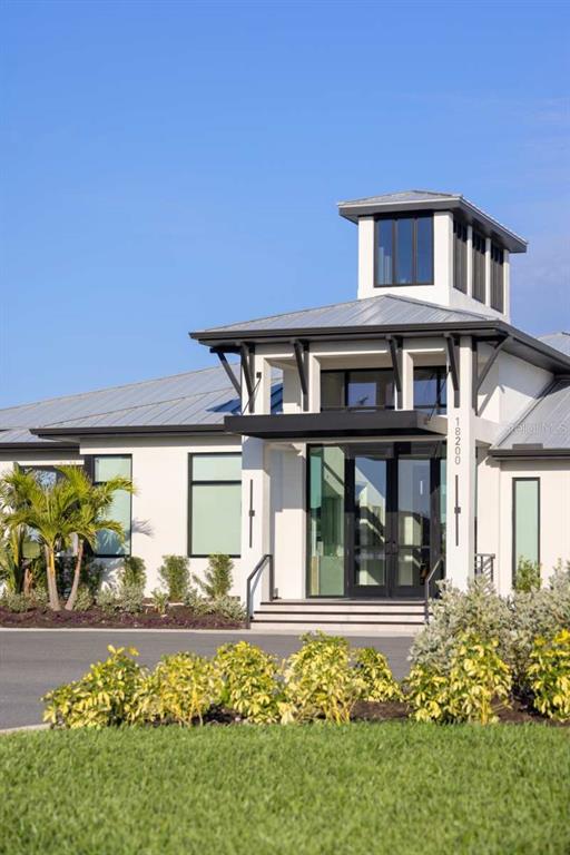 A modern white building with a metal roof, glass double doors, and a central tower — 12024 ETHOS COURT, VENICE, FL