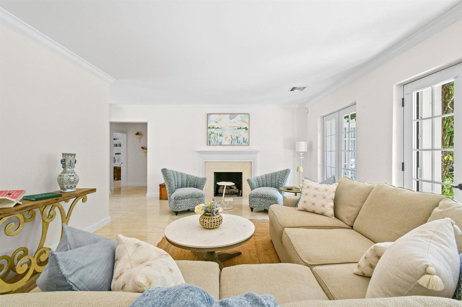 A living room with a fireplace, beige sectional sofa, and two blue patterned armchairs — 117 Via Vizcaya, Palm Beach FL 33480, PALM BEACH, FL