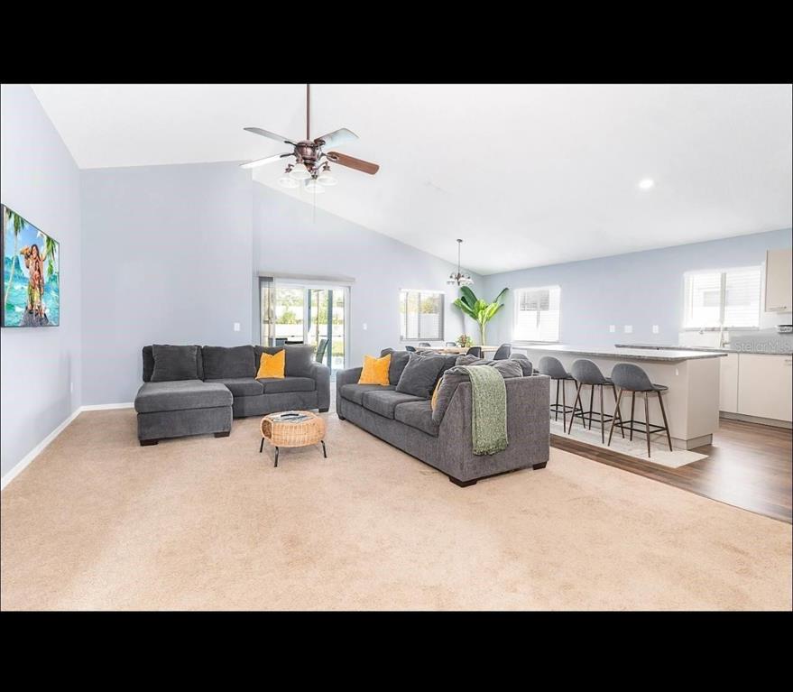 A living room with gray sofas, carpeted flooring, and an open kitchen with a breakfast bar — 2609 MONTEGO BAY BOULEVARD, KISSIMMEE, FL