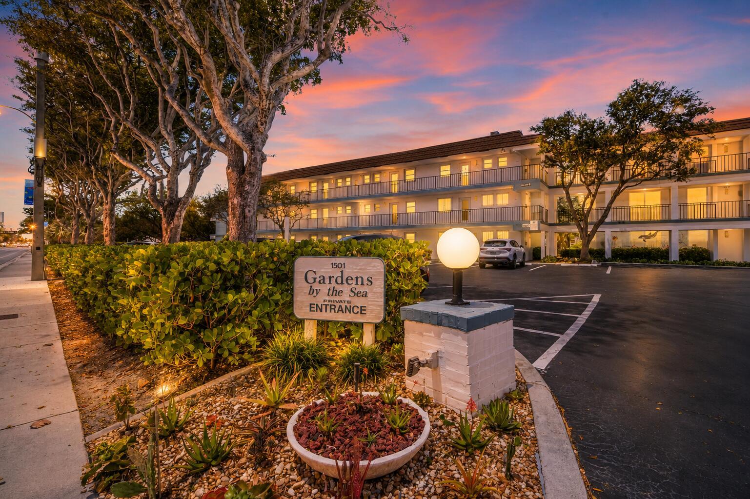 An exterior view of a multi-story apartment building at sunset with a private entrance sign — 1501 S Ocean Boulevard # 123, Pompano Beach FL 33062, POMPANO BEACH, FL