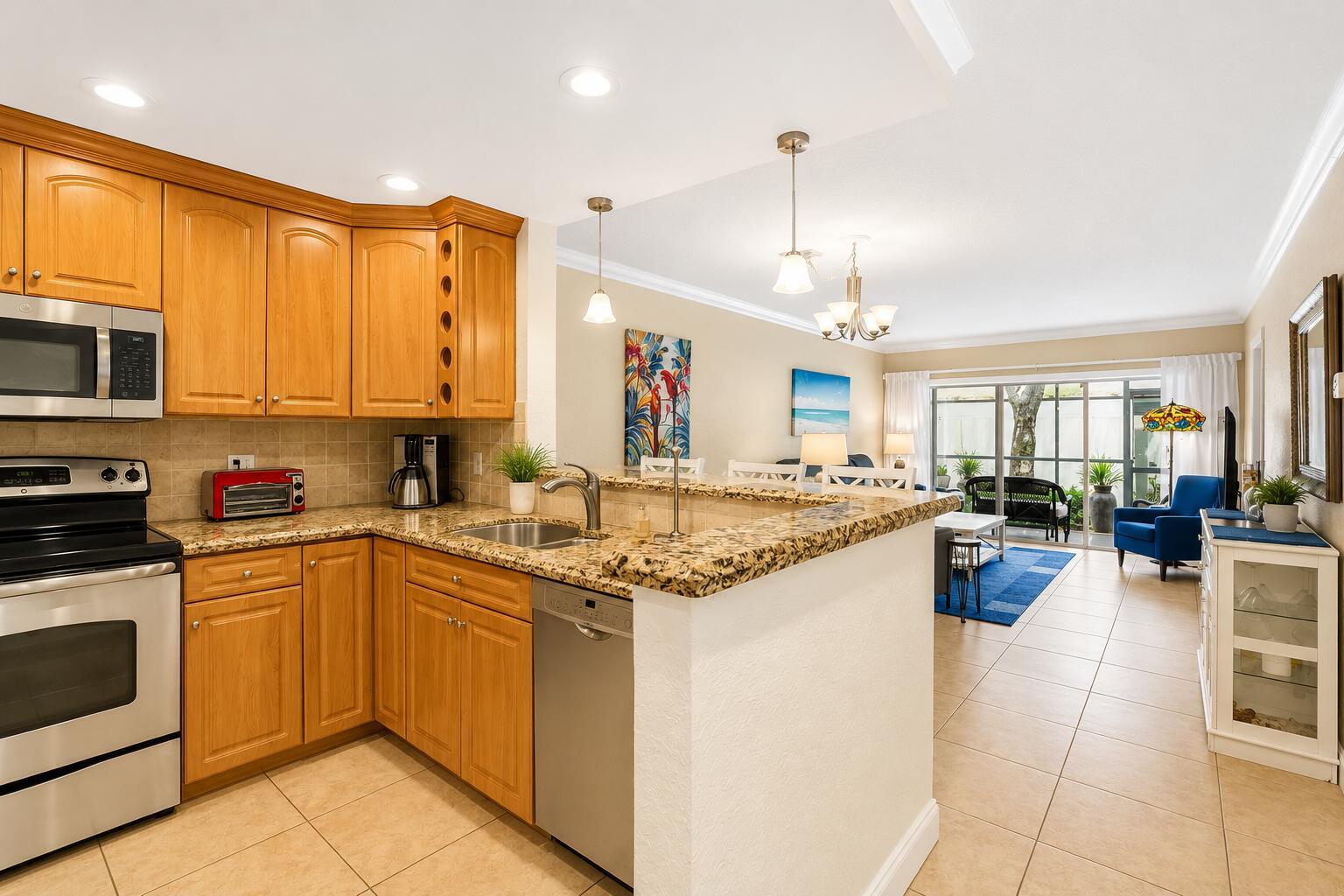 A kitchen with wood cabinets and granite countertops overlooks a living area with a patio — 1501 S Ocean Boulevard # 123, Pompano Beach FL 33062, POMPANO BEACH, FL