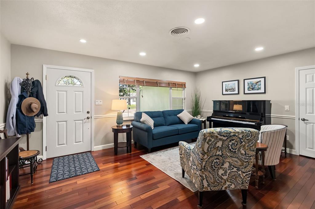 A living room features a blue sofa, a patterned armchair, a piano, and hardwood floors — 616 BRECHIN DRIVE, WINTER PARK, FL