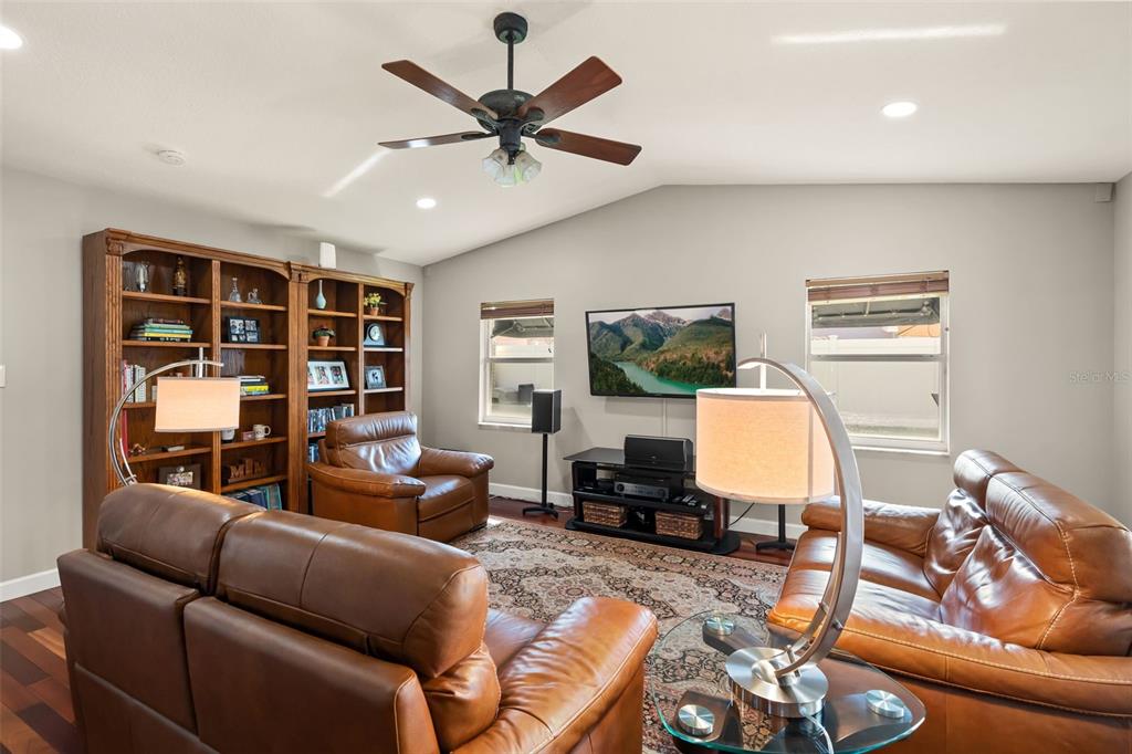 A living room features leather furniture, a wooden bookshelf, a ceiling fan, and a television — 616 BRECHIN DRIVE, WINTER PARK, FL