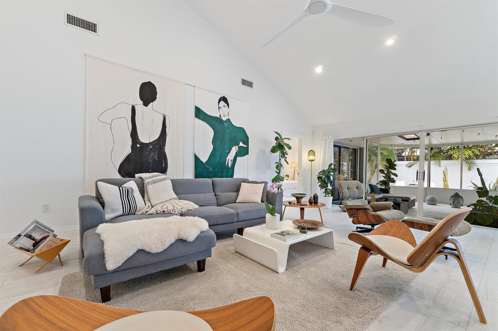 A bright living room features a gray sofa, modern wooden chairs, and large wall art — 125 Harbourside Circle, Jupiter FL 33477, JUPITER, FL